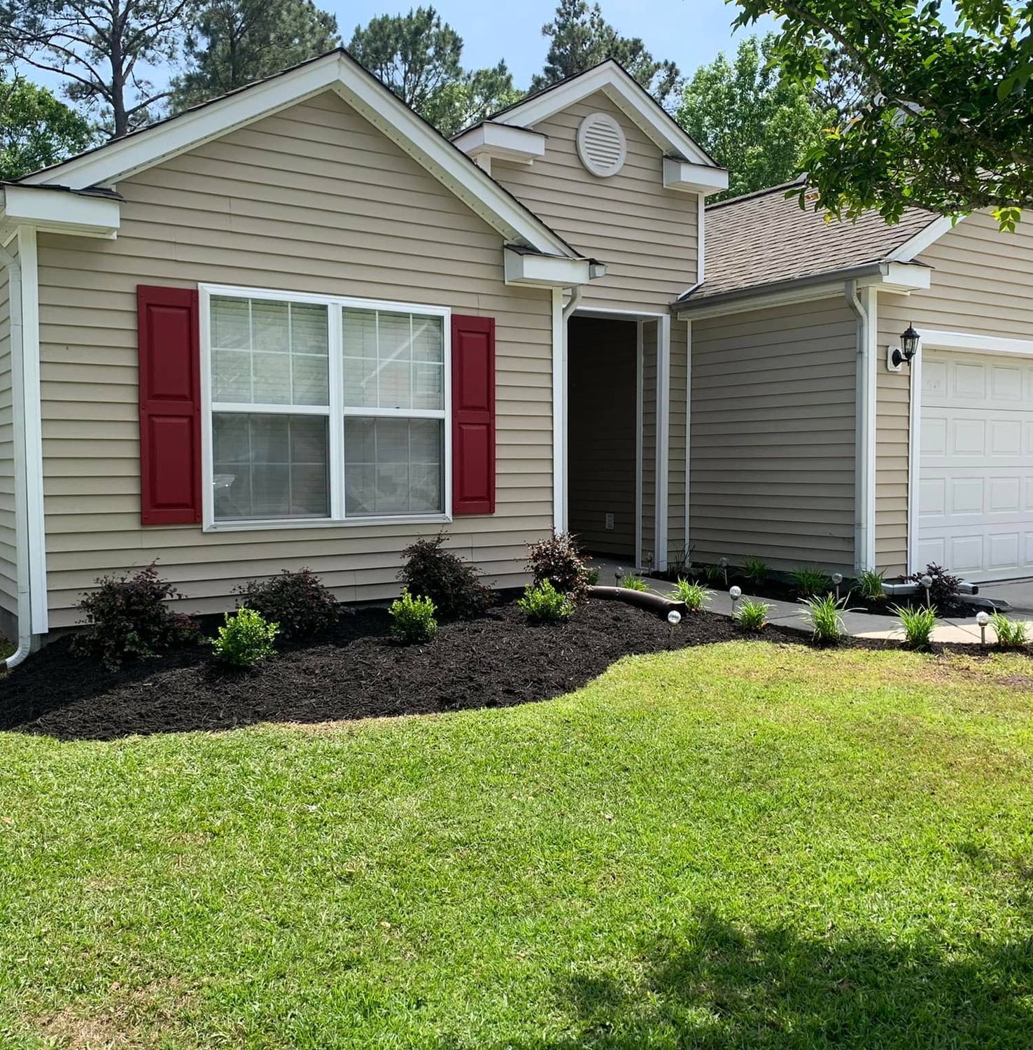 Beautiful home with freshly mulched garden beds and manicured lawn