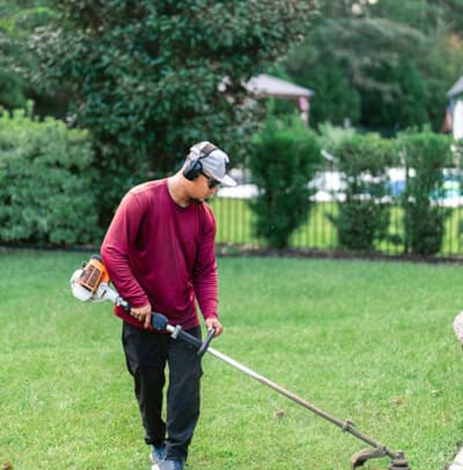 Professional landscaper using string trimmer on residential property